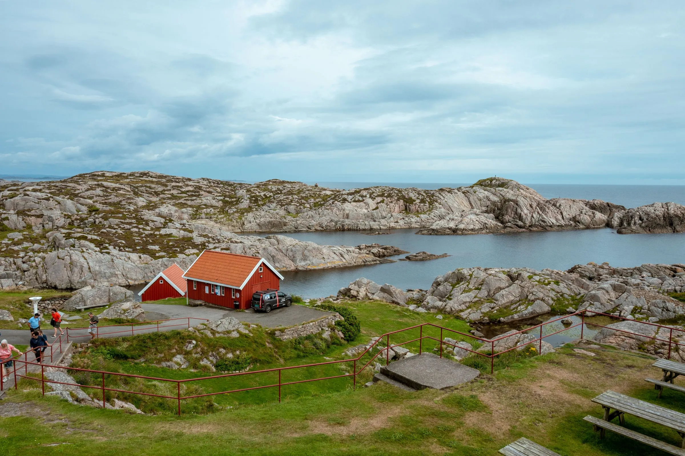 Red coastal cabins among low granite shelves beside a calm inlet.